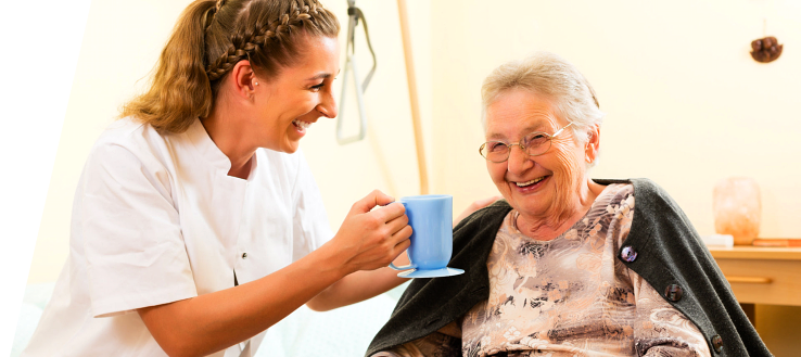 Caregiver serving coffee to an elderly woman
